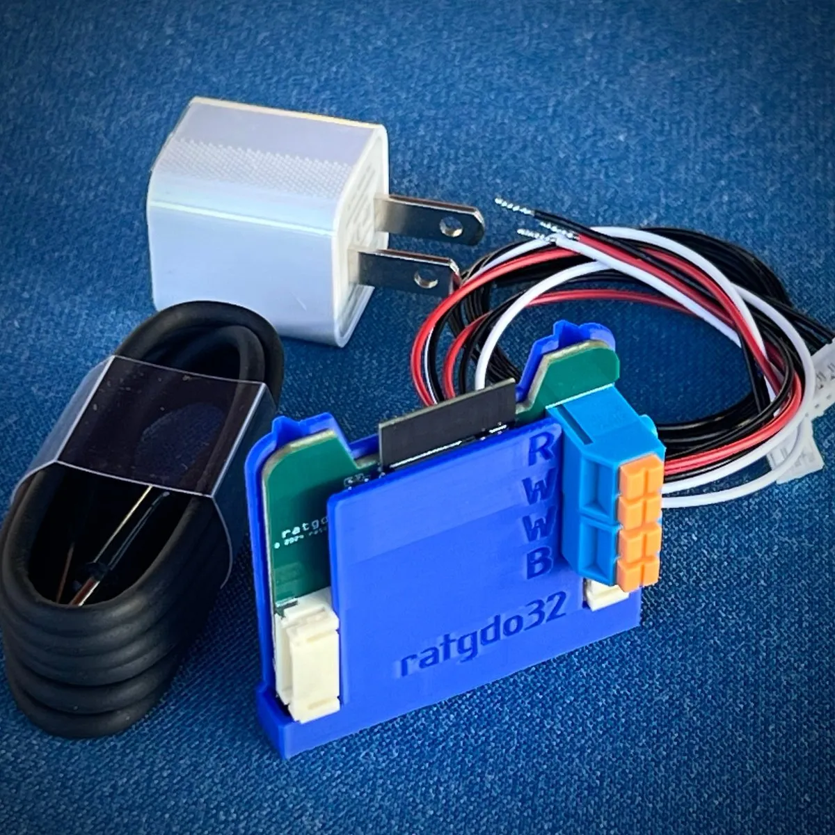 A small blue circuit-board controller with wires, a USB cable, and a power adapter.